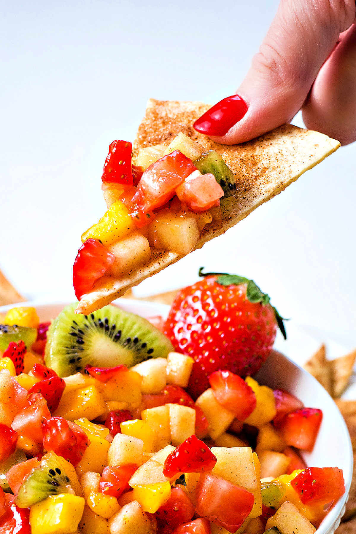 dipping a cinnamon tortilla chip into a bowl of fruit salsa.