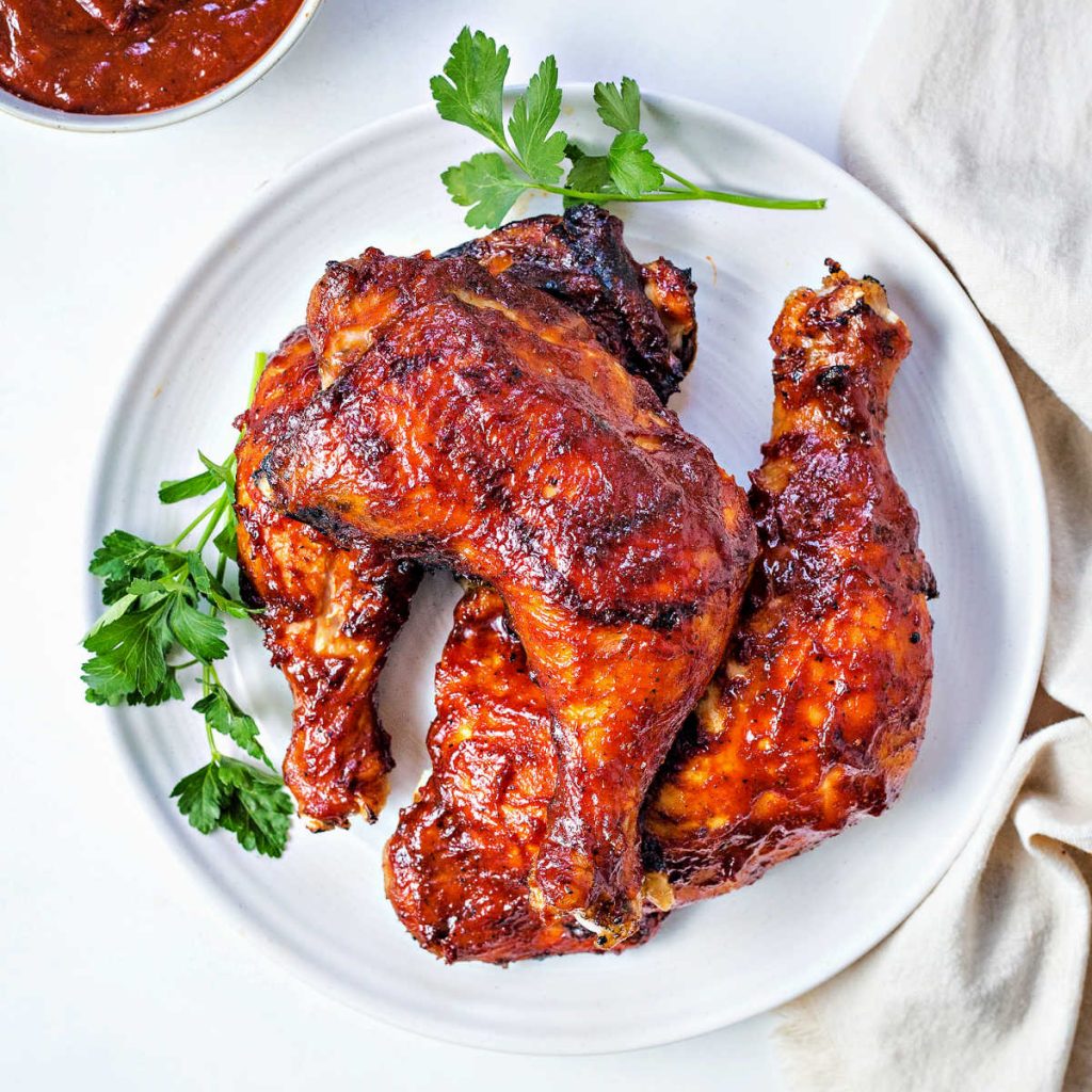 oven barbecue chicken leg quarters on a plate garnished with parsley.