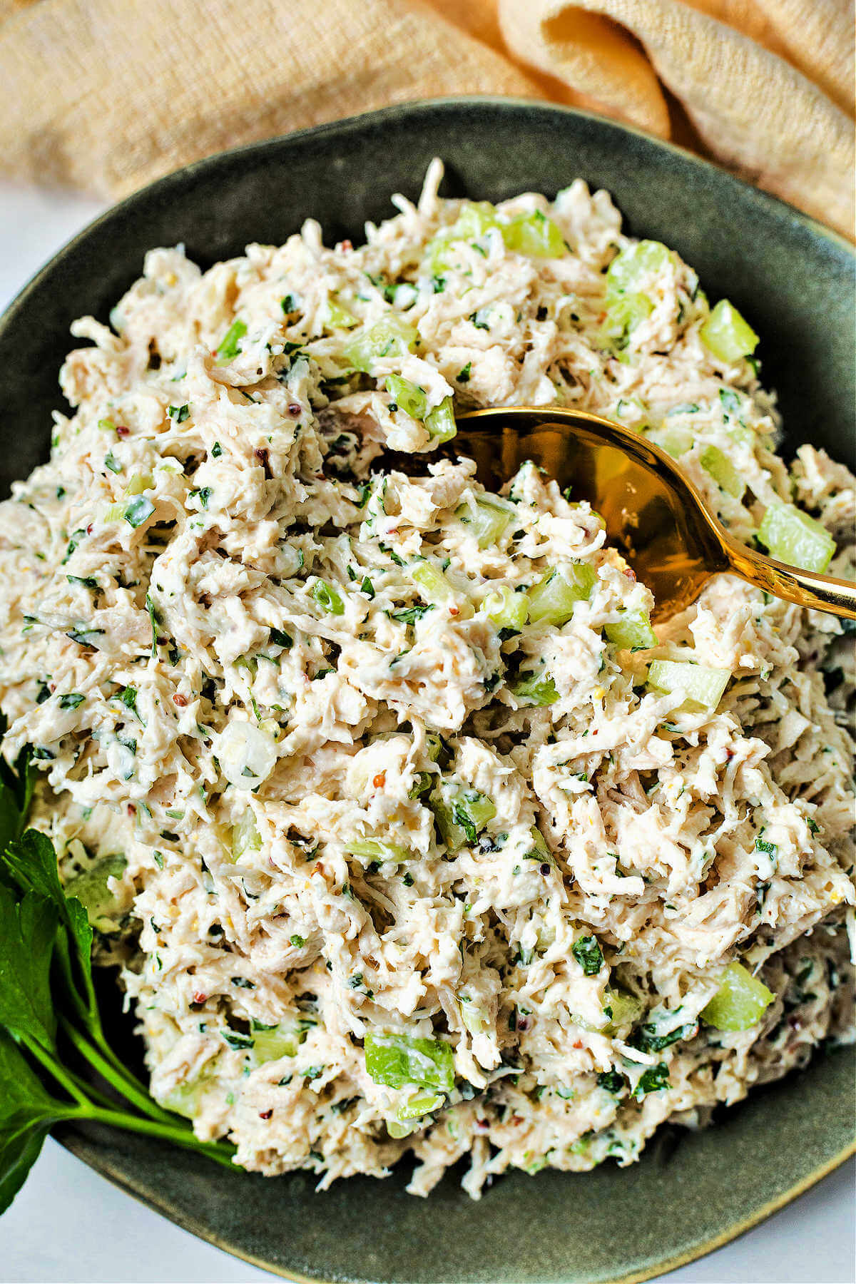 a bowl of chicken salad with a spoon inserted.