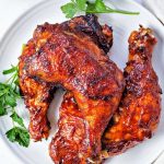 oven barbecue chicken leg quarters on a plate garnished with parsley.