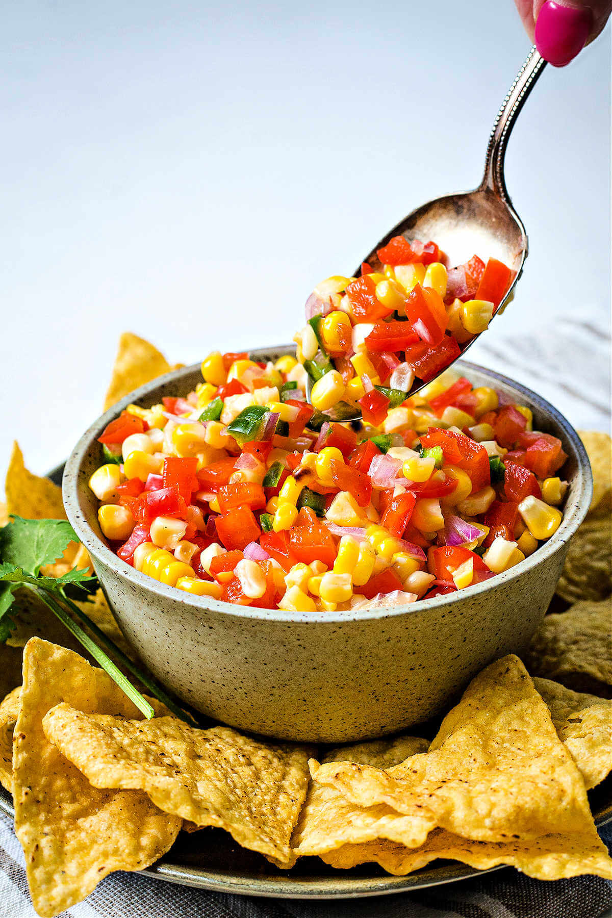 spooning corn salsa into a serving bowl.