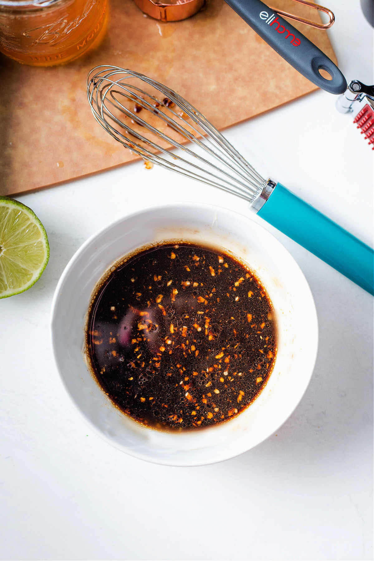 a bowl of pork chop marinade on a table with a wire whisk to the side.