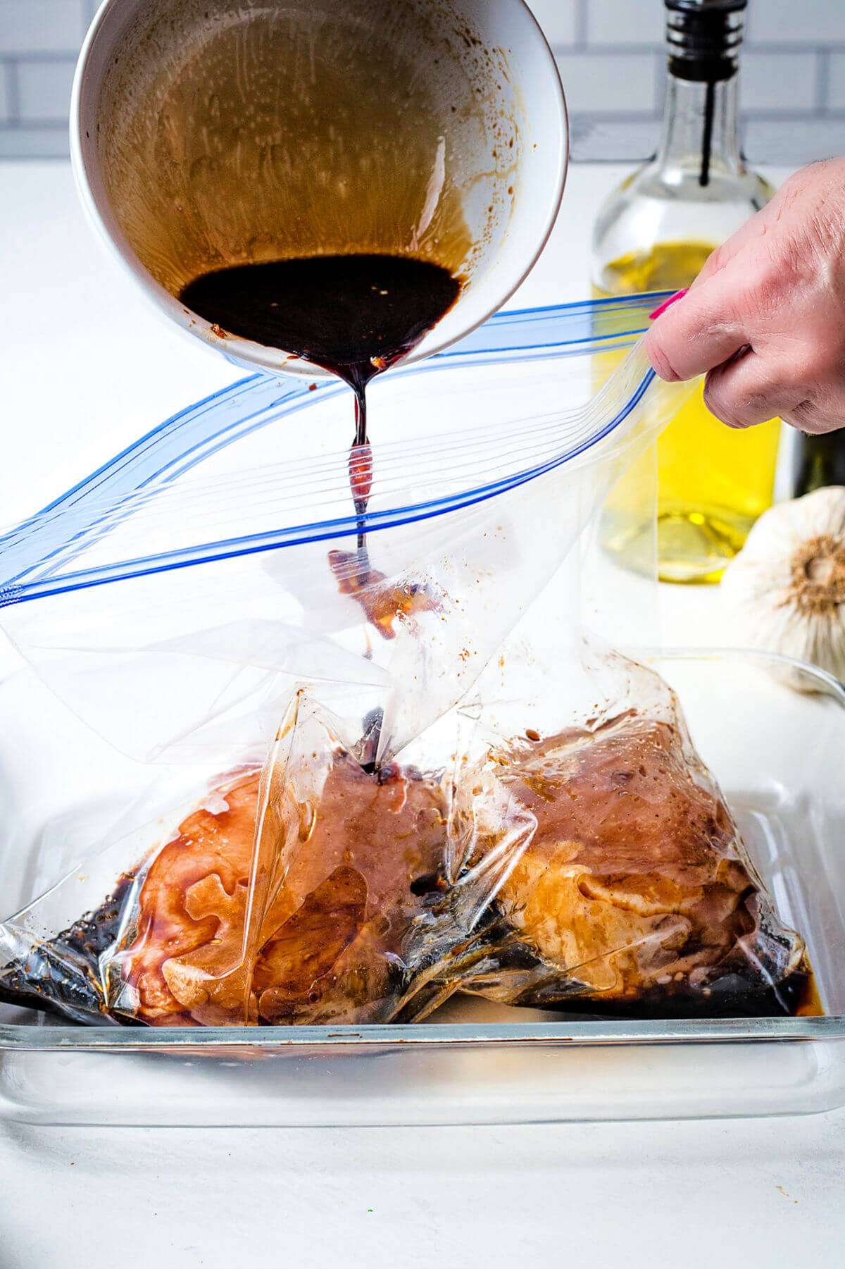 pouring pork chop marinade into a gallon size ziplock bag with pork chops inside.