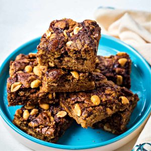 peanut butter brownies stacked on top of each other on a blue plate.