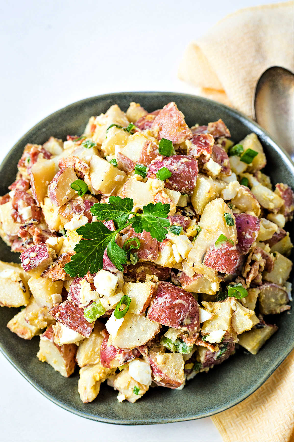 red potato salad on a green plate with a yellow napkin.