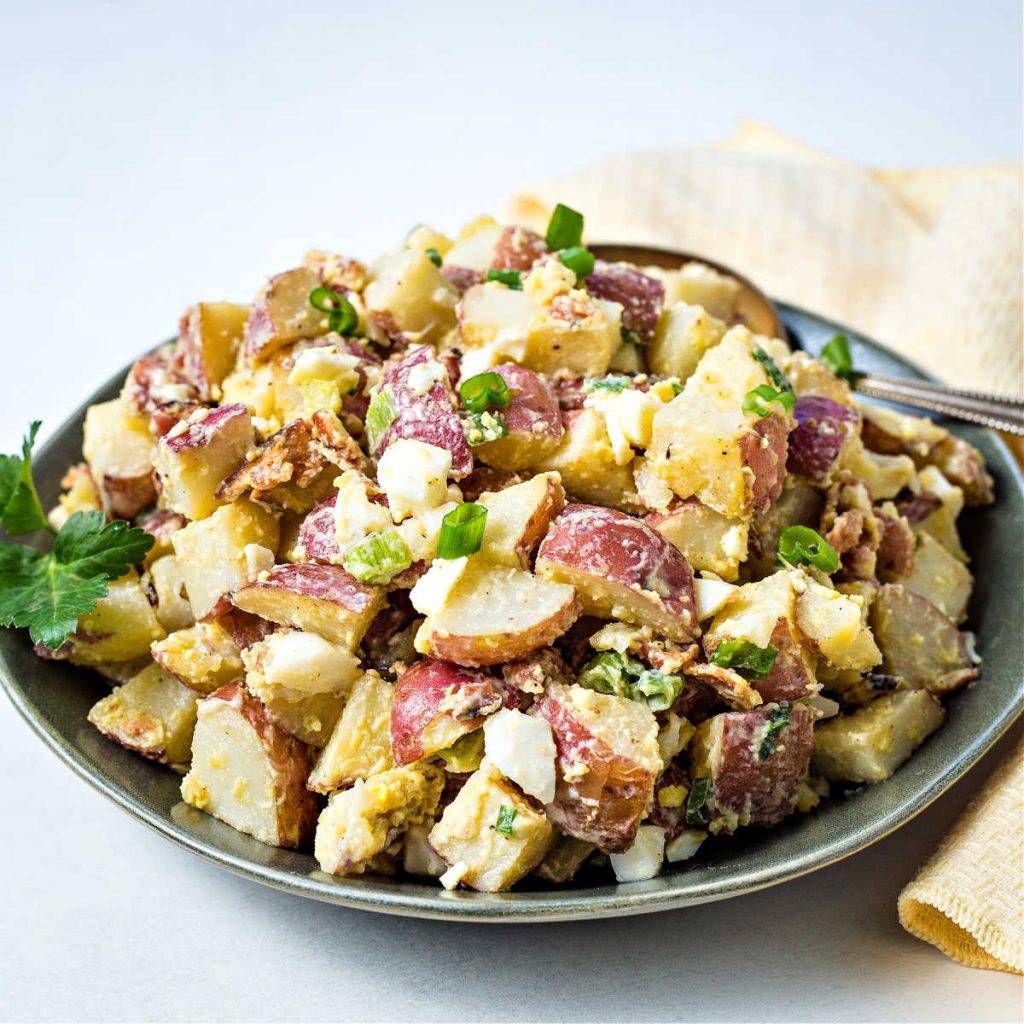 red potato salad on a green plate with a yellow napkin.