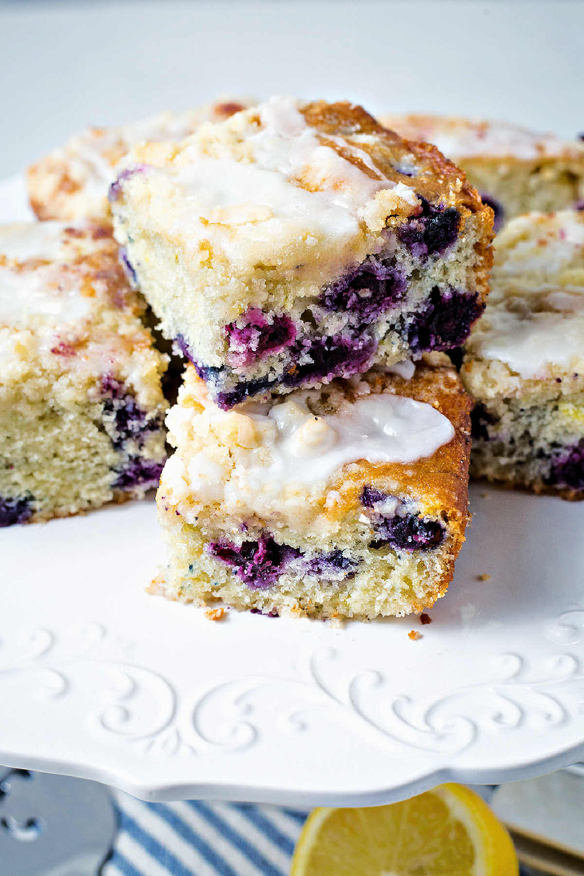 pieces of blueberry crumb cake stacked on a cake pedestal.