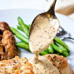 a spoon ladeling mustard sauce over chicken cutlets on a plate.