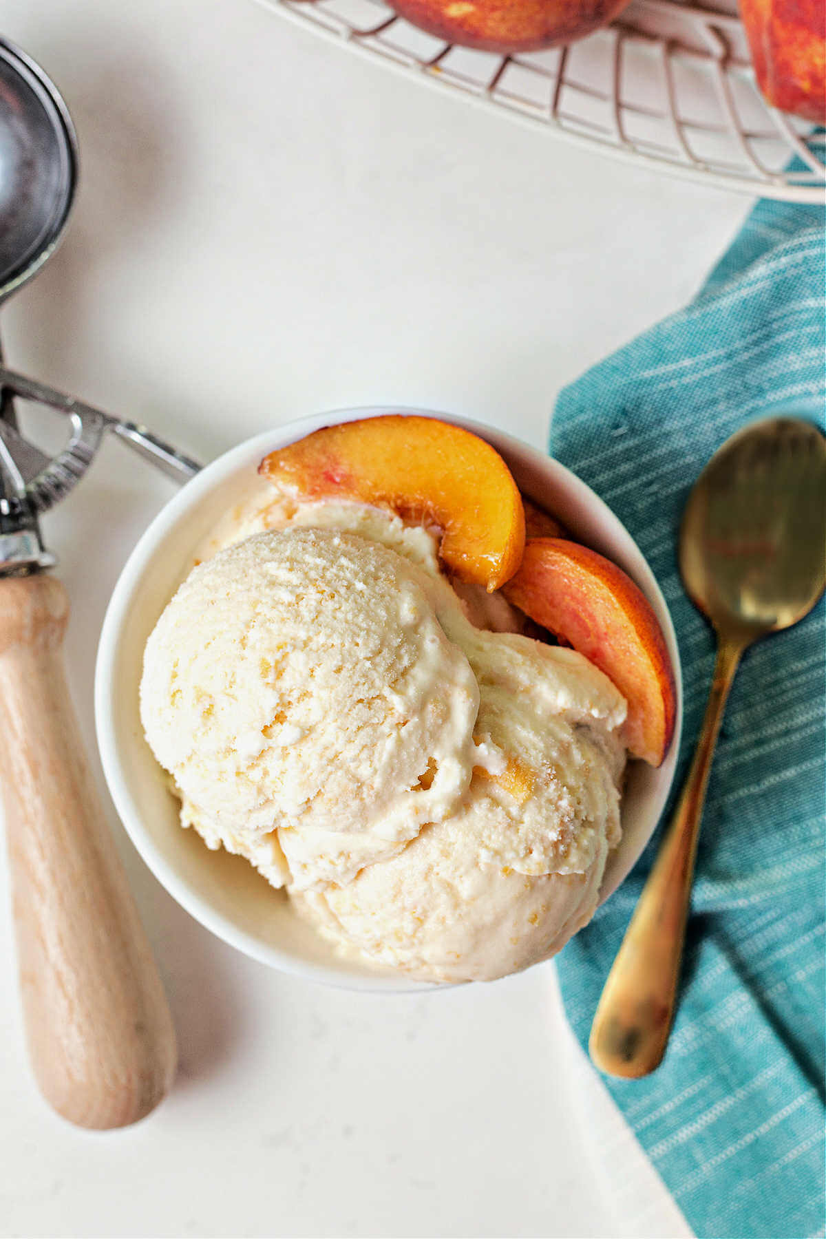 a bowl of peach ice cream with peach slices on the side.