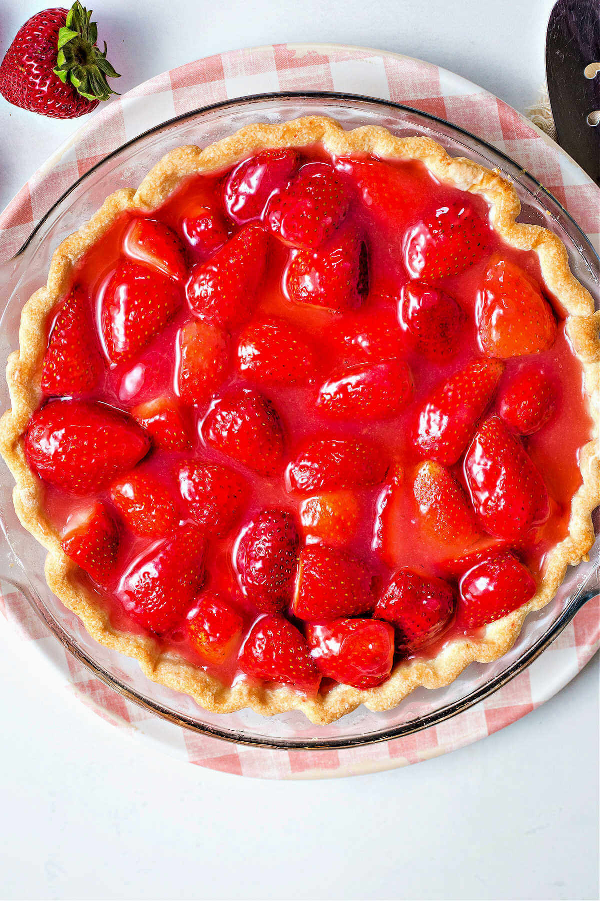 a fresh strawberry pie sitting on a decorative plate.