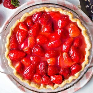 a fresh strawberry pie sitting on a decorative plate.