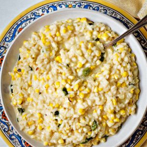 arroz poblano in a bowl sitting on a decorative plate on a table with a spoon.