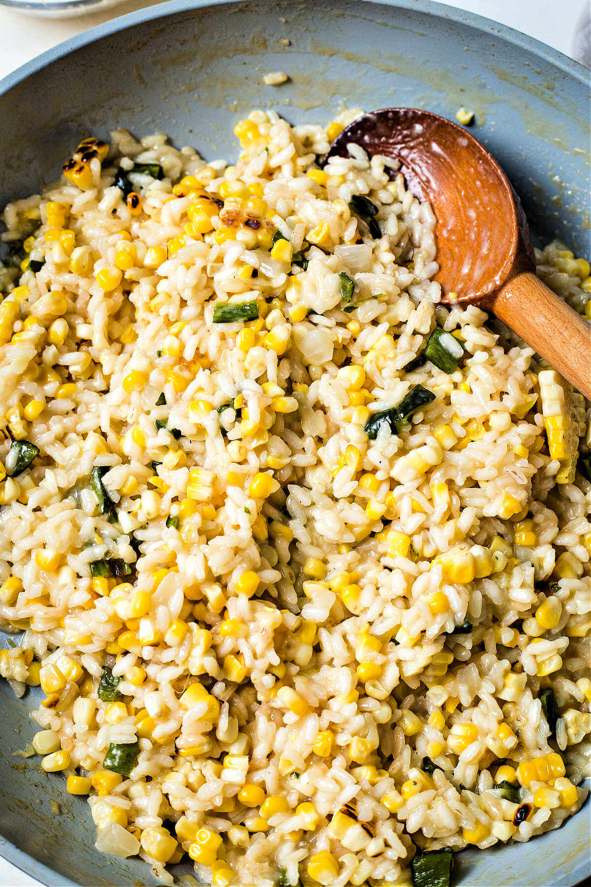 stirring arroz poblano in a skillet with a wooden spoon.