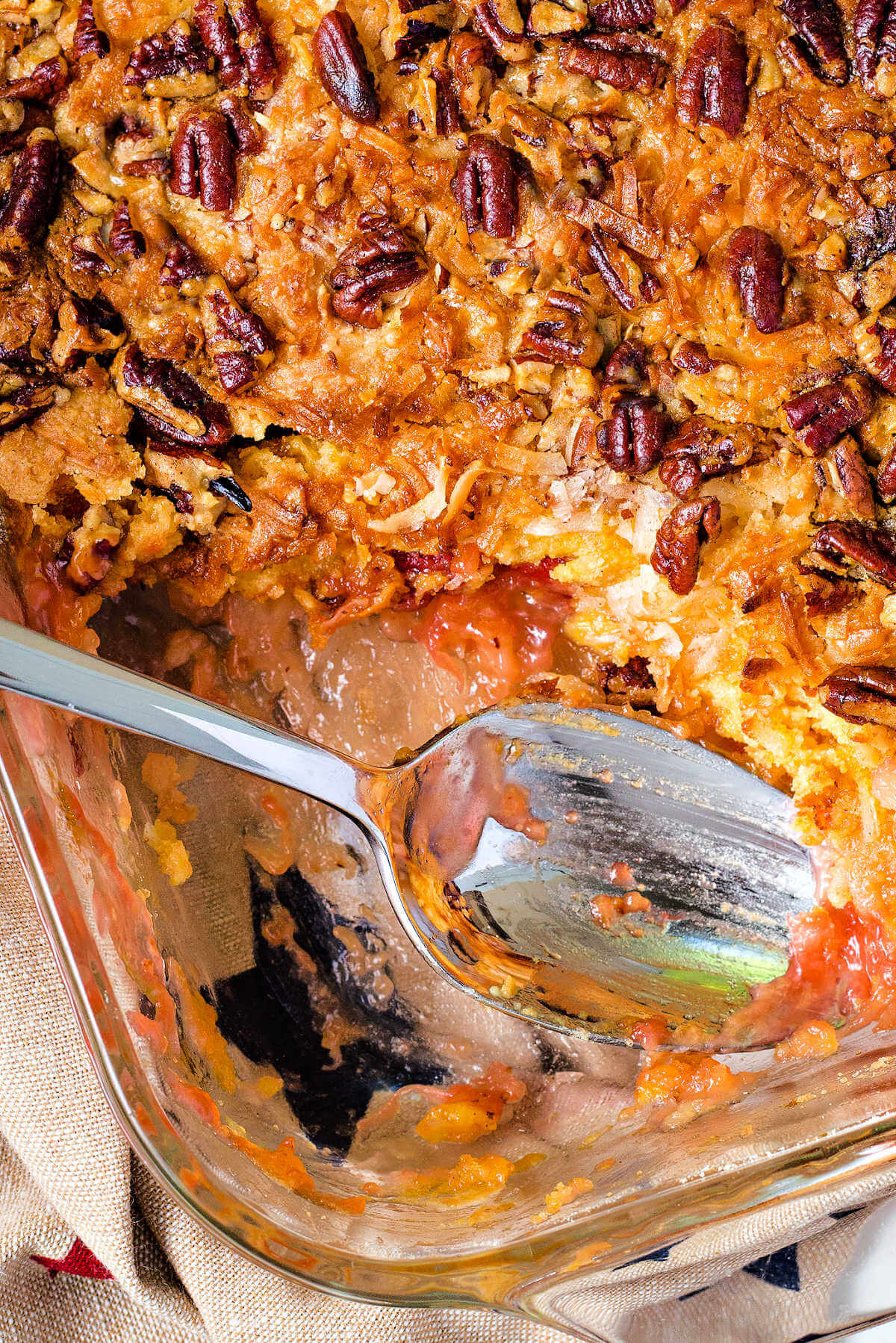 cherry dump cake in a glass dish with a serving spoon inserted.