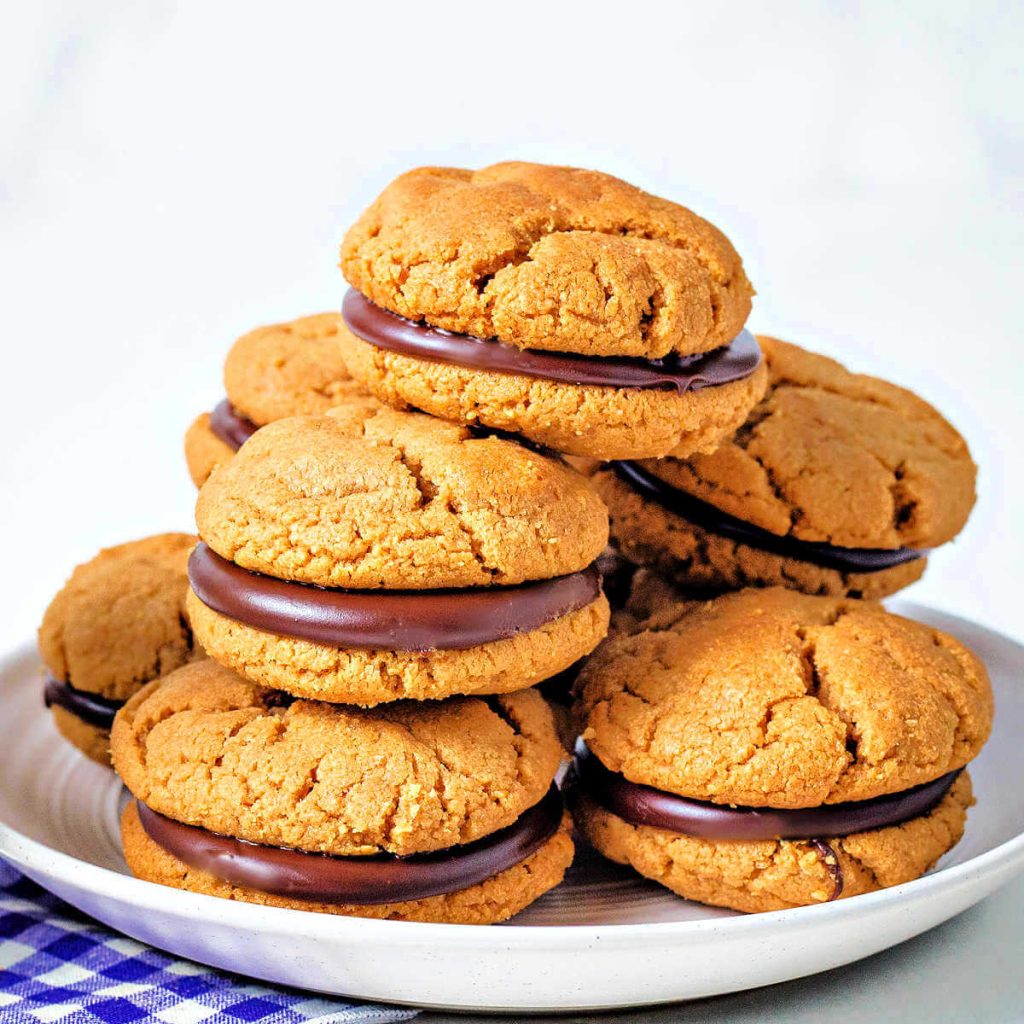 peanut butter sandwich cookies stacked on a white plate.