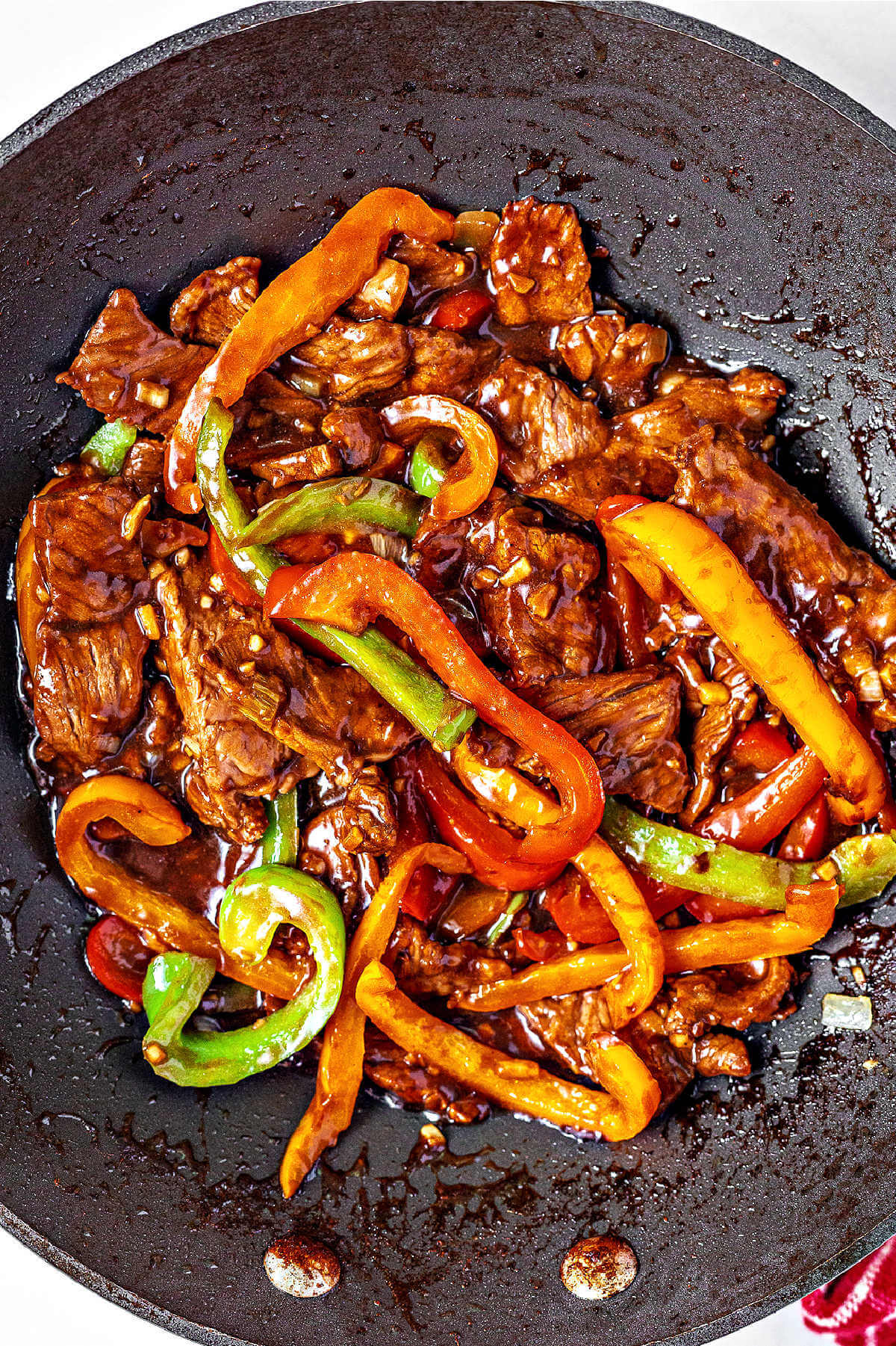 pepper steak simmering in sauce in a wok.