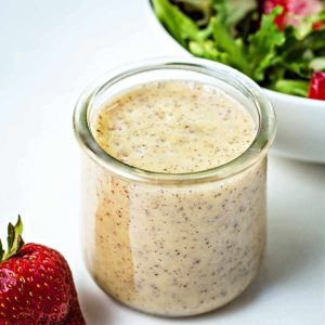 poppy seed dressing in a small glass jar on a table.