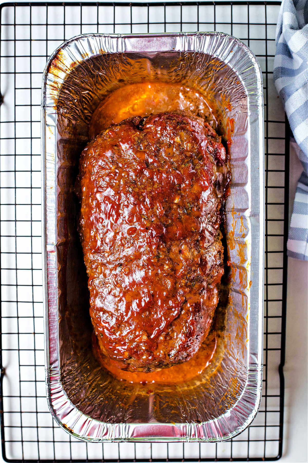 smoked meatloaf in an aluminum pan on a cooling rack.