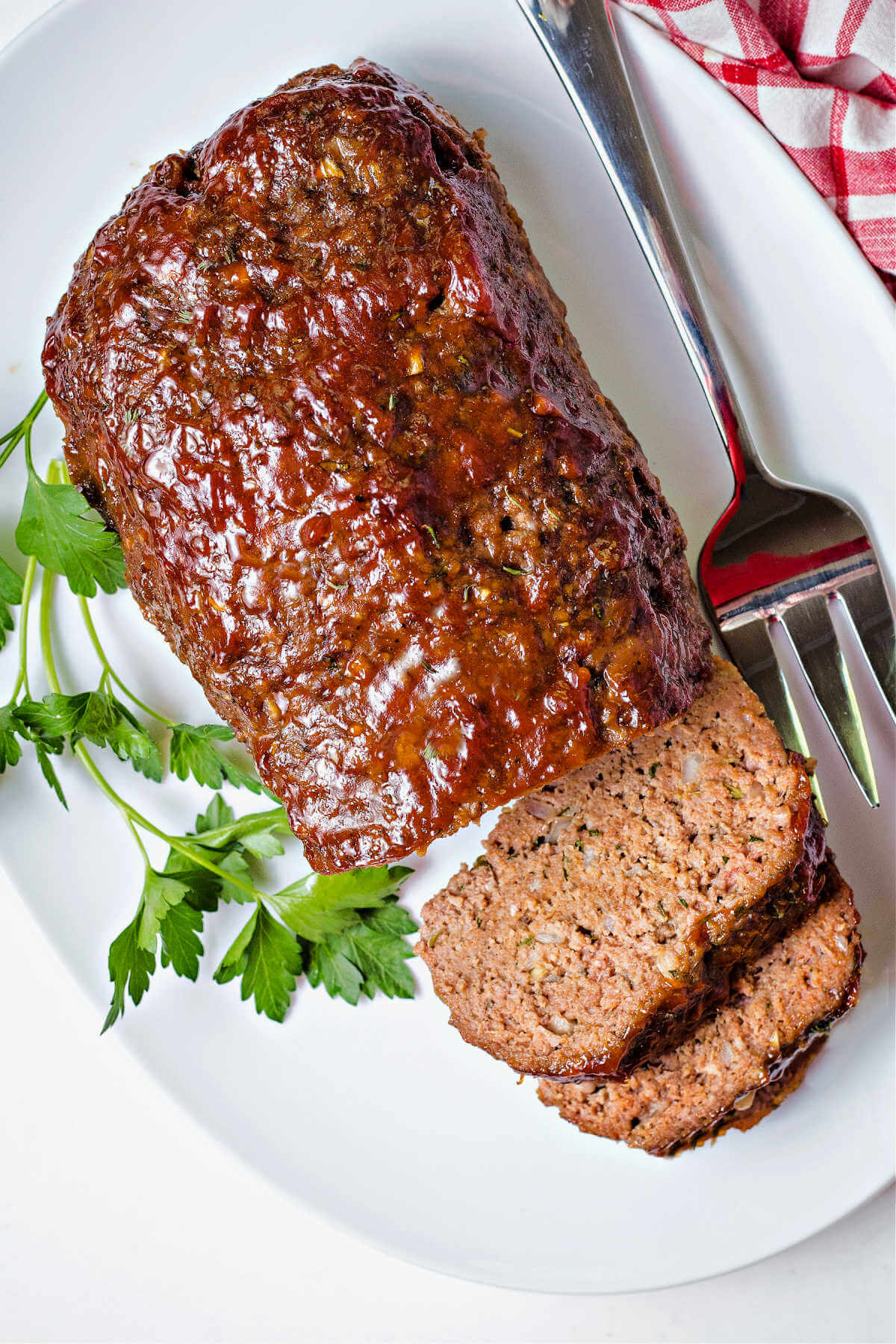 slices of smoked meatloaf on a serving platter with a meat fork.