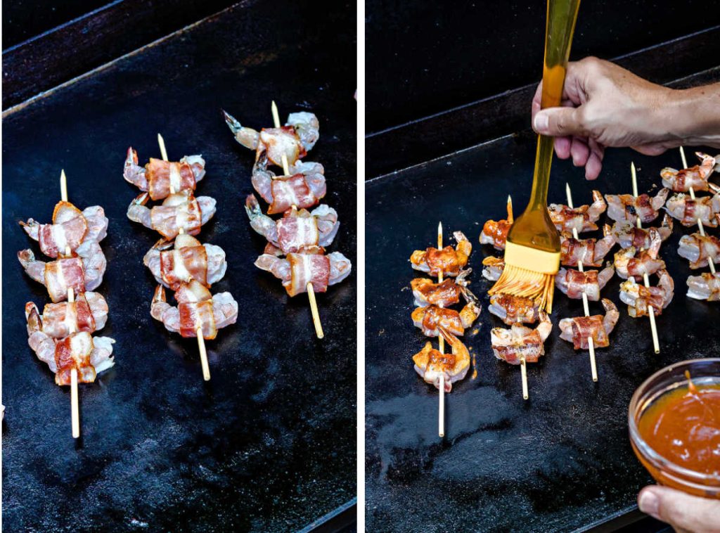 skewers of shrimp on a blackstone griddle; basting bacon wrapped shrimp with barbecue sauce.