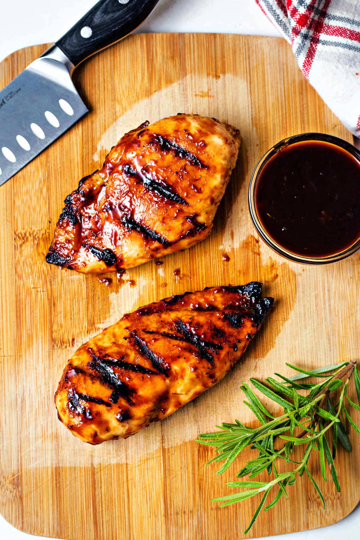 grilled balsamic glazed chicken on a cutting board with fresh rosemary.