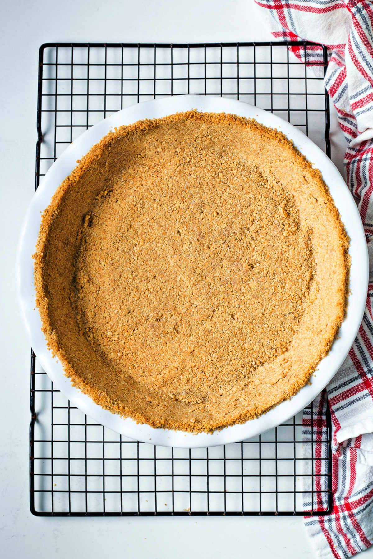 a baked graham cracker crust on a wire cooling rack.