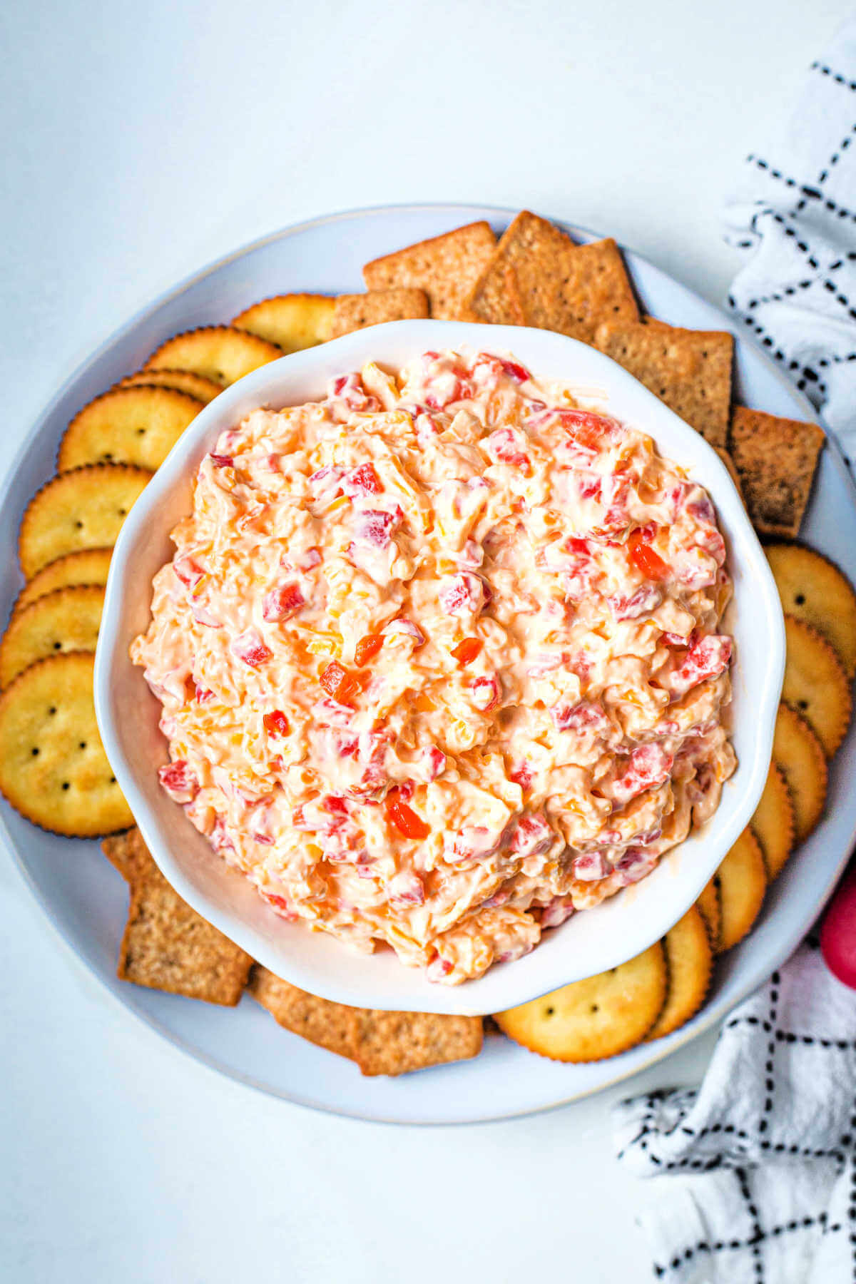 a bowl mounded full with homemade pimento cheese with crackers on a plate.