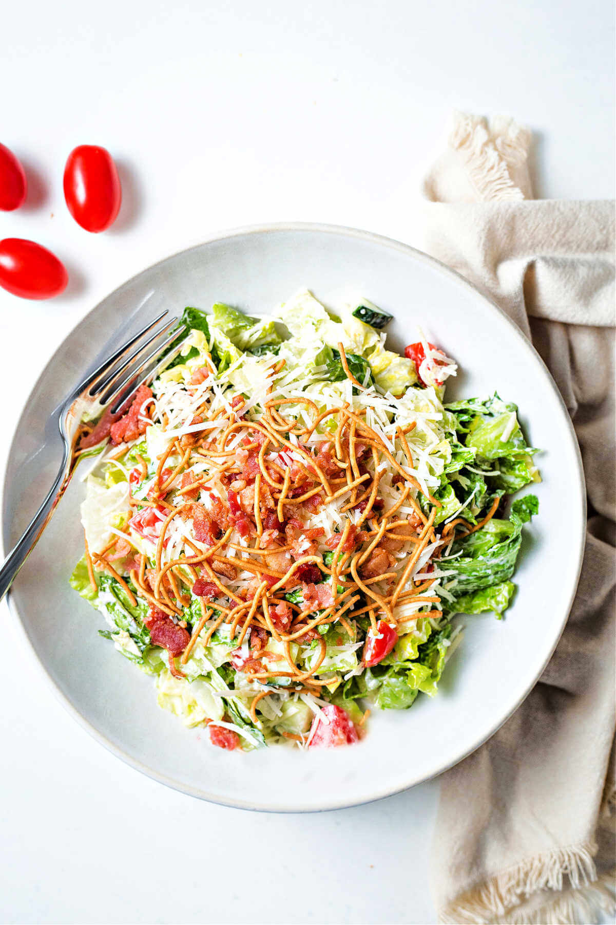 Bravo's chopped salad in a white bowl on a table with a napkin and fork.