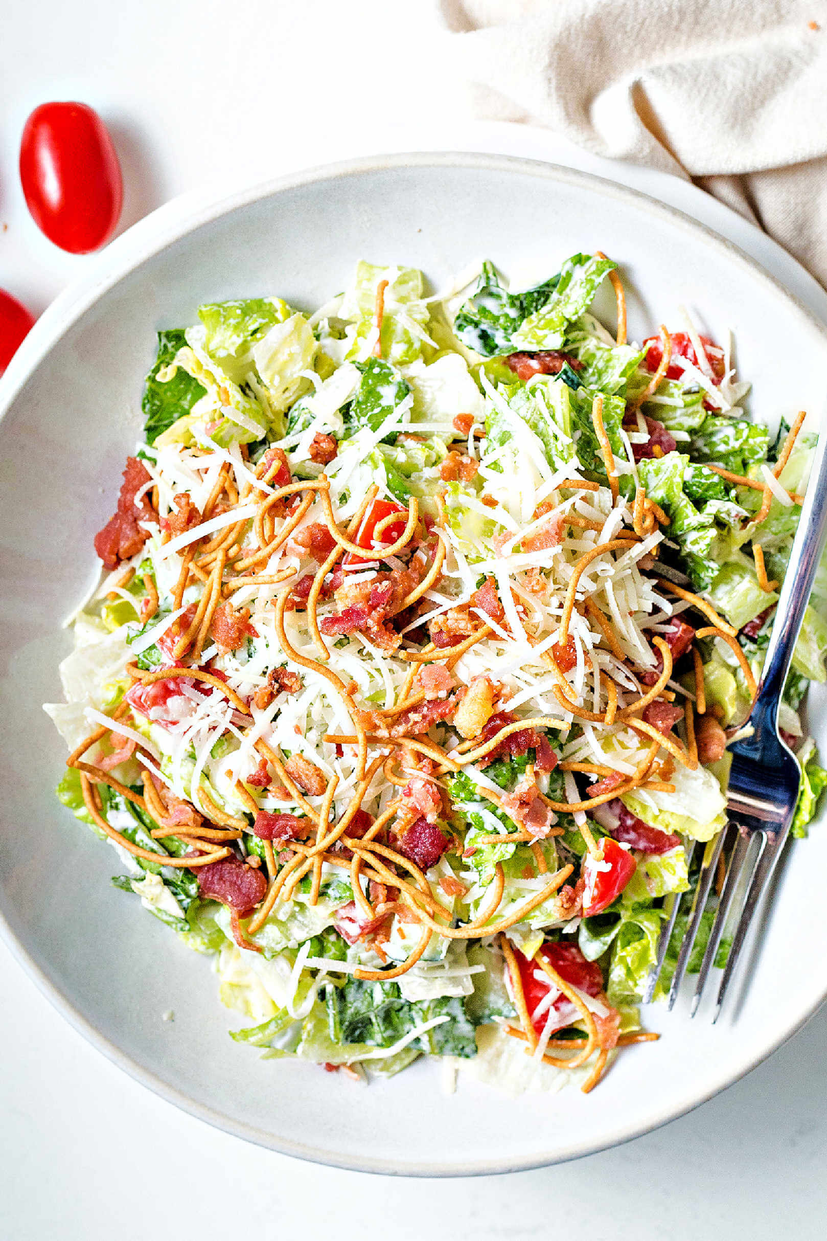 Bravo's chopped salad in a white bowl on a table with a napkin and fork.