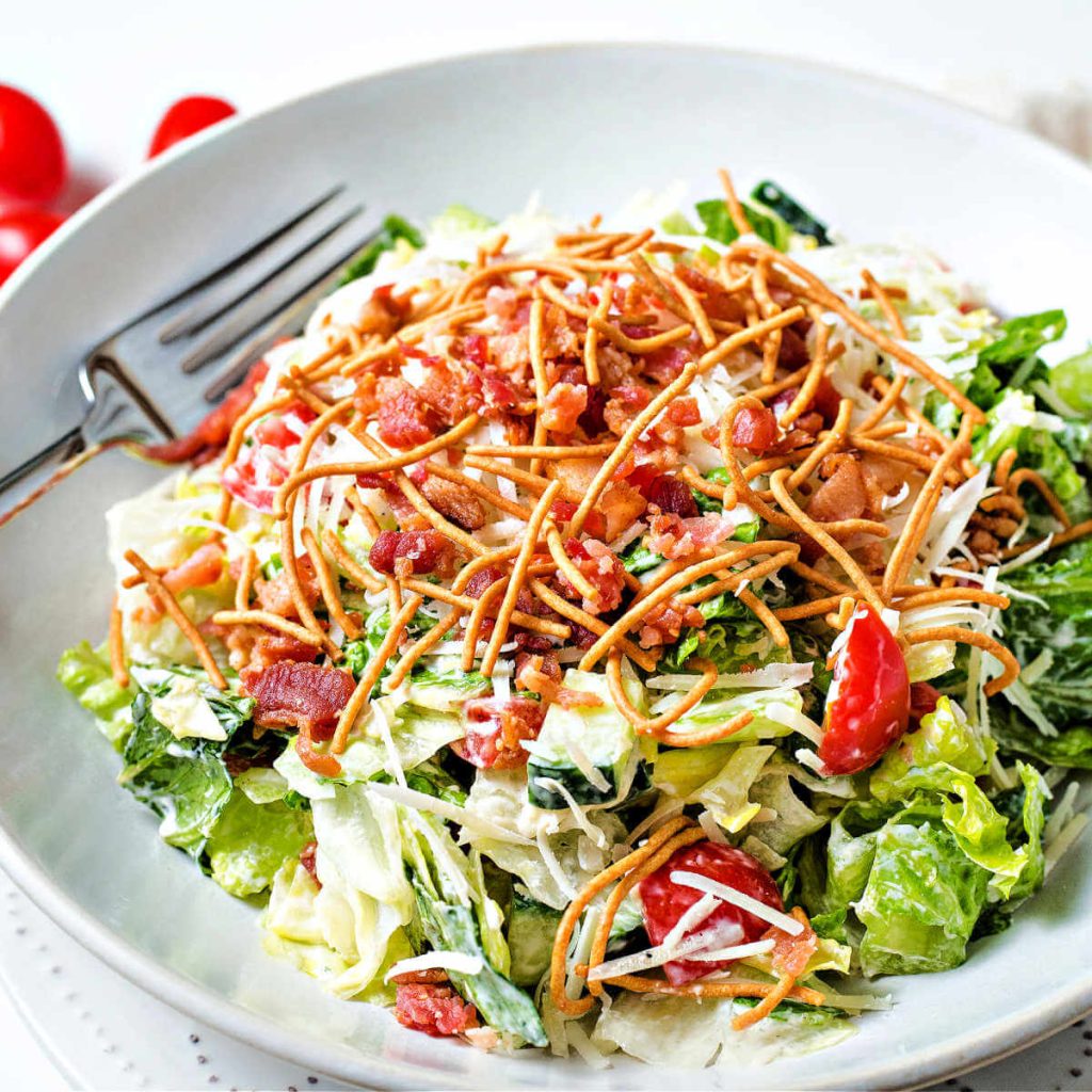 Bravo's chopped salad, Insalata Della Casa, in a white bowl with a fork sitting on a table.