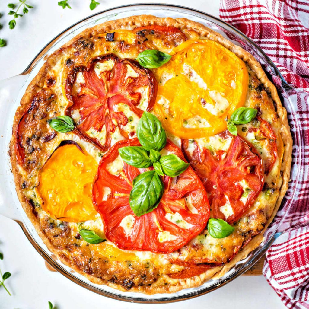 a whole baked tomato pie garnished with basil sprigs.