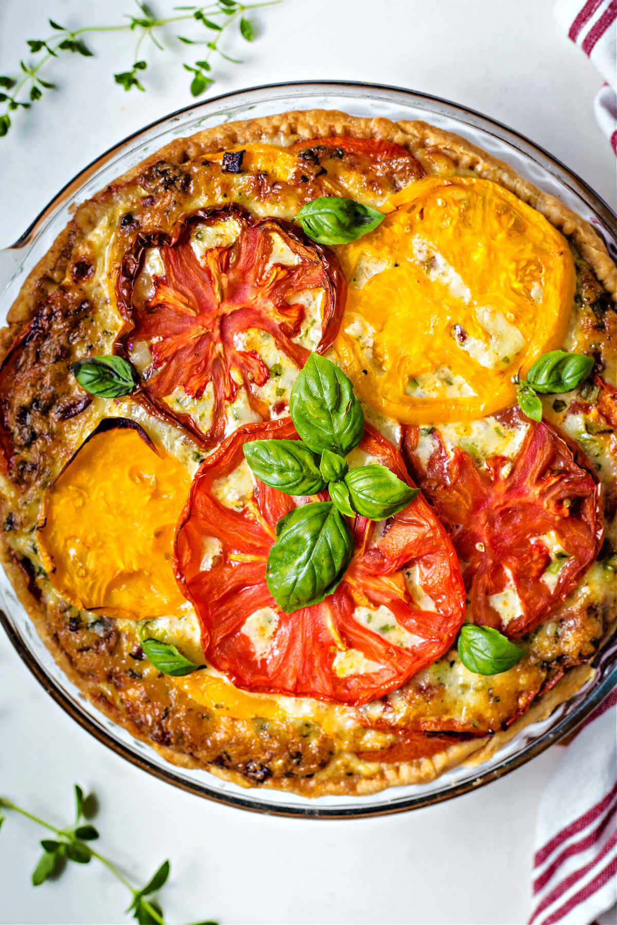 a whole baked tomato pie garnished with basil sprigs.