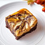 a pumpkin cheesecake brownie on a dessert plate.
