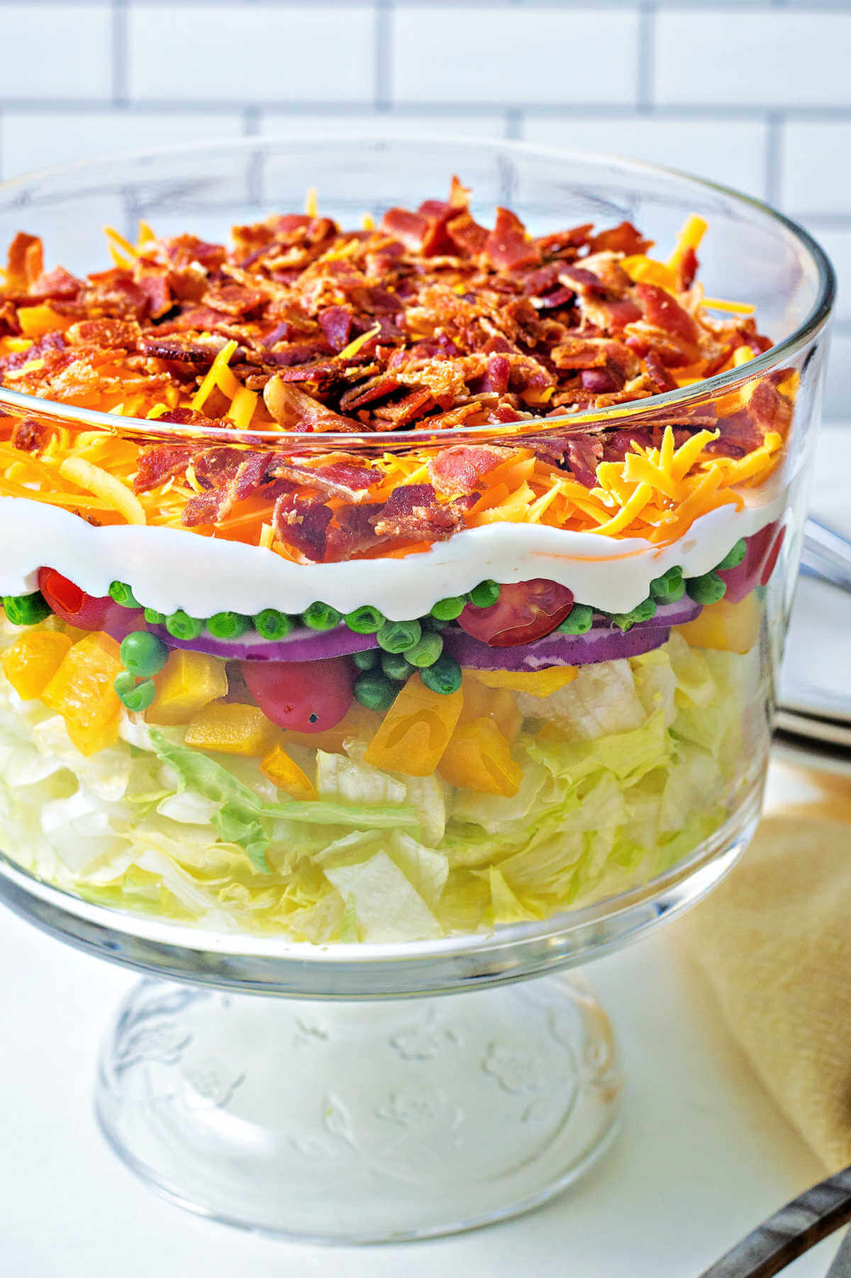 7 layer salad in a glass bowl sitting on a counter.