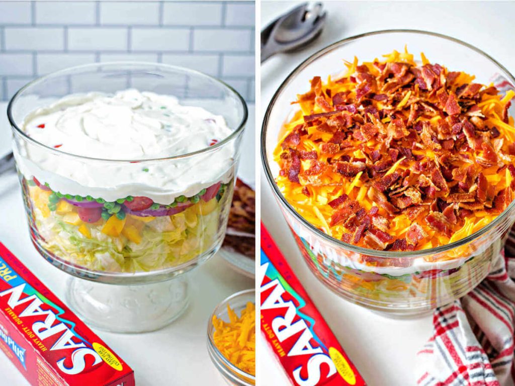 7 layer salad in a trifle bowl topped with cheddar cheese and bacon