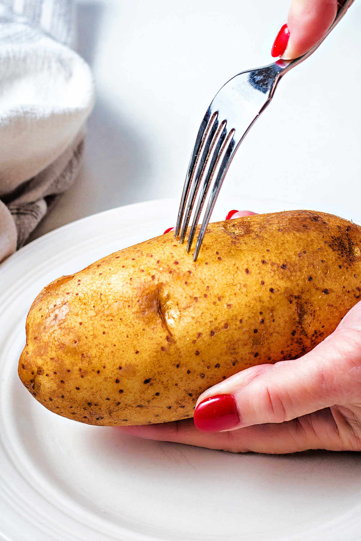 piercing a raw unpeeled potato with a fork.