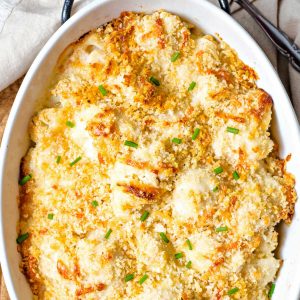 cauliflower gratin with toasted breadcrumbs and garnished with chopped chives in a baking dish.