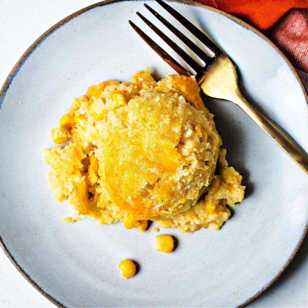 a mounded scoop of corn pudding on a plate.