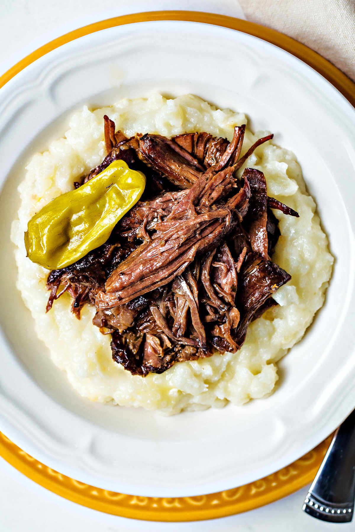 shredded Mississippi pot roast piled on top of a mound of mashed potatoes.