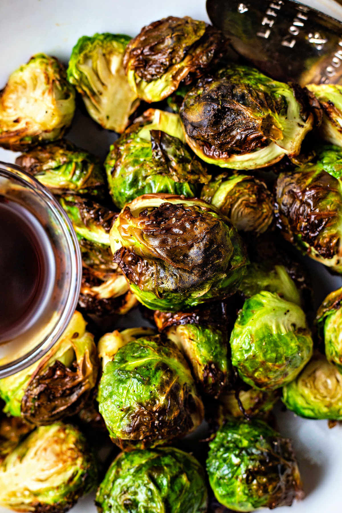 crispy air fryer brussels sprouts in a white bowl with a dipping sauce.