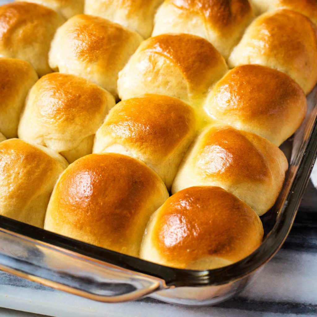 a pan of baked dinner rolls basted with butter.