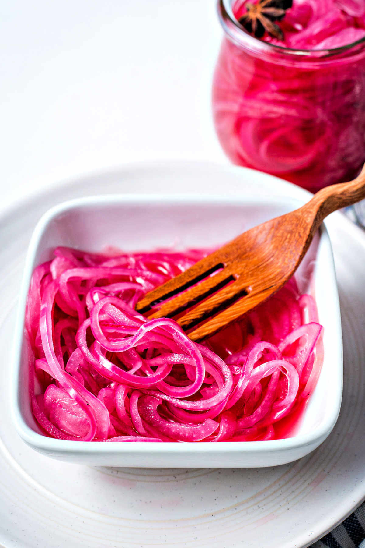 a bowl of pickled red onions with a wooden fork.