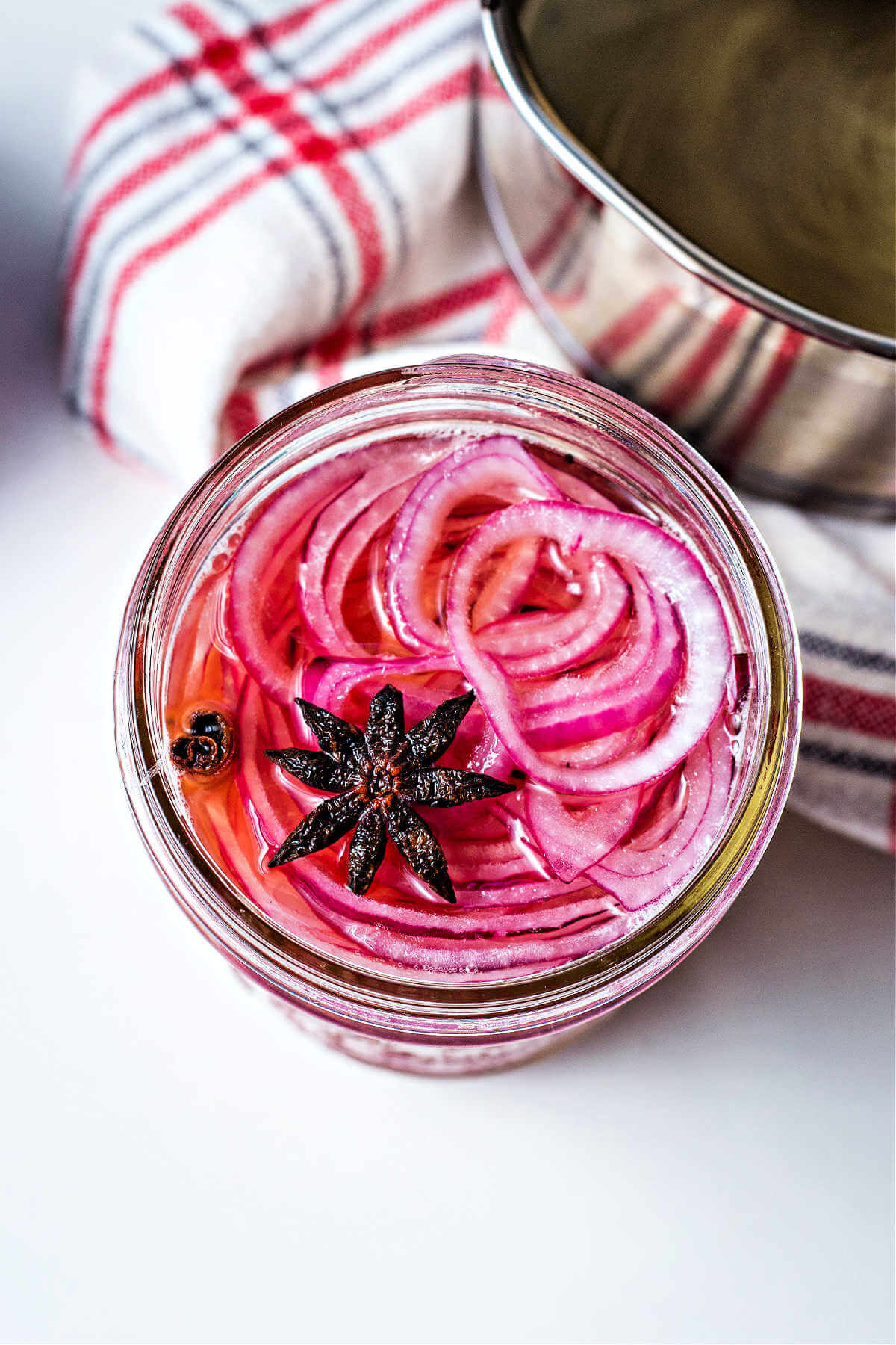 a jar of red onion slices filled with brine to make pickled red onions.