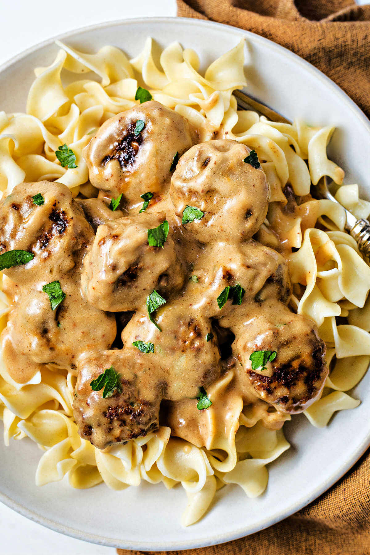 Swedish meatballs with gravy over a bowl of egg noodles.