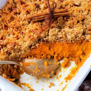 sweet potato souffle in a white baking dish with a serving scooped out.