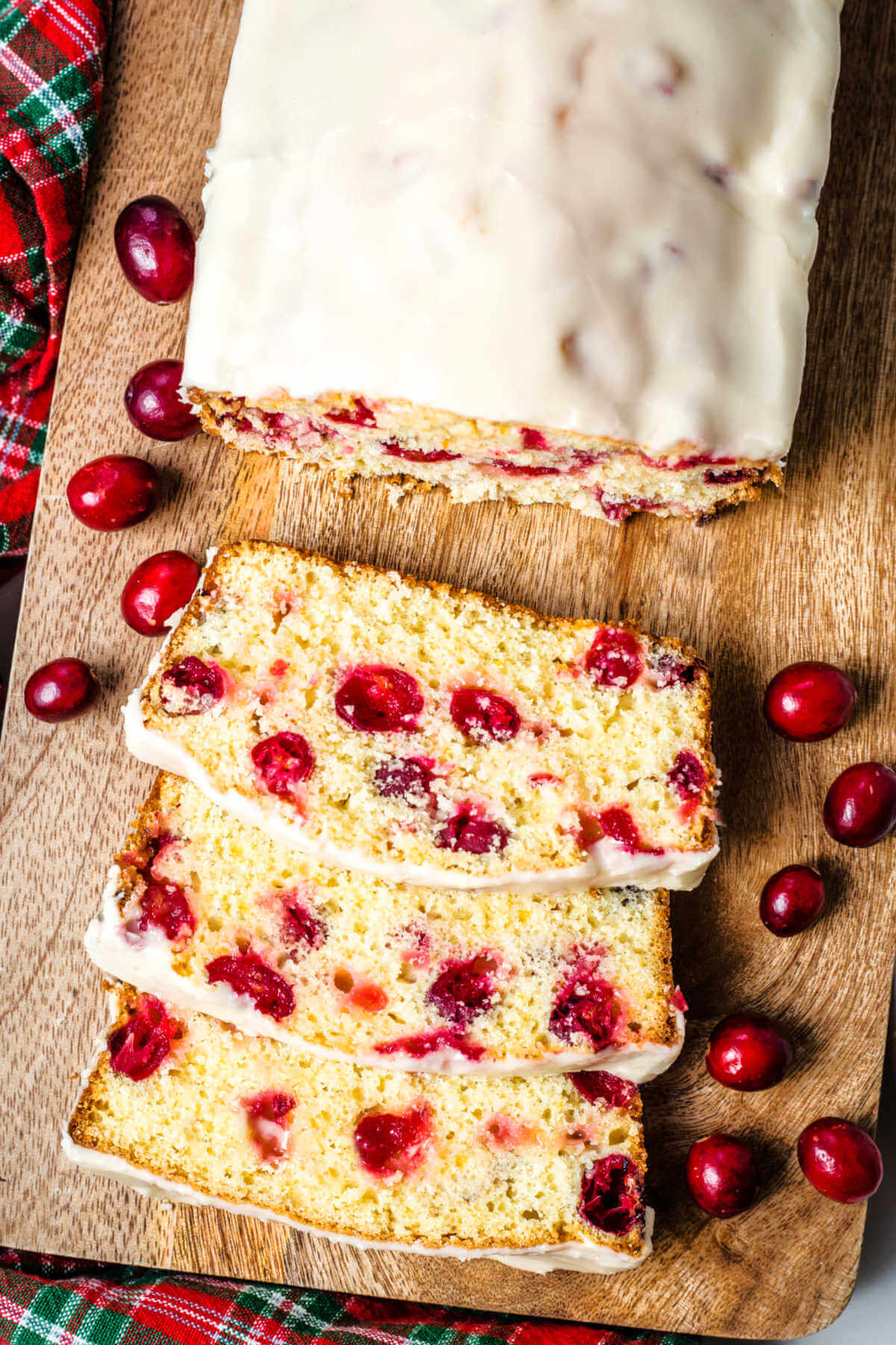 cranberry orange bread on a wooden tray with cranberries scattered around.