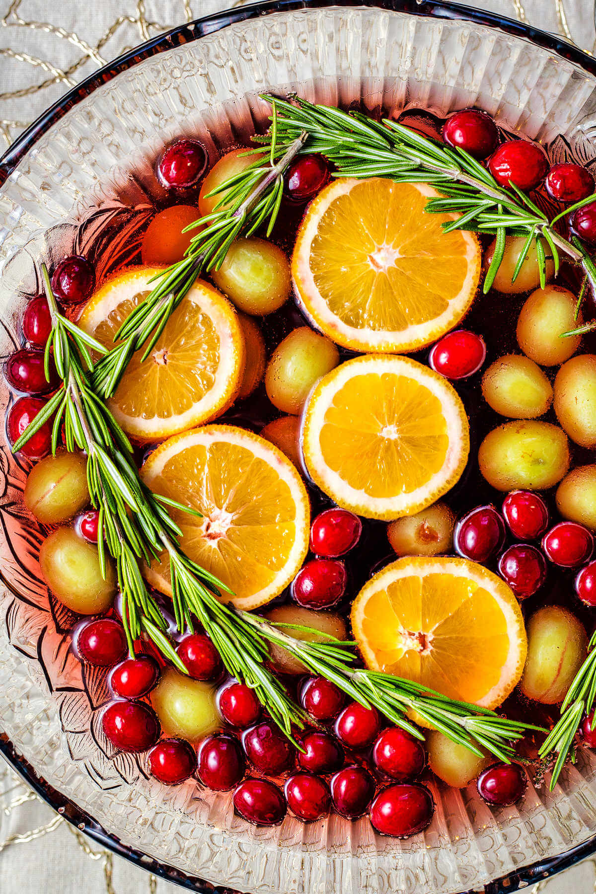 a punch bowl filled with white grape punch with floating fruit on top.