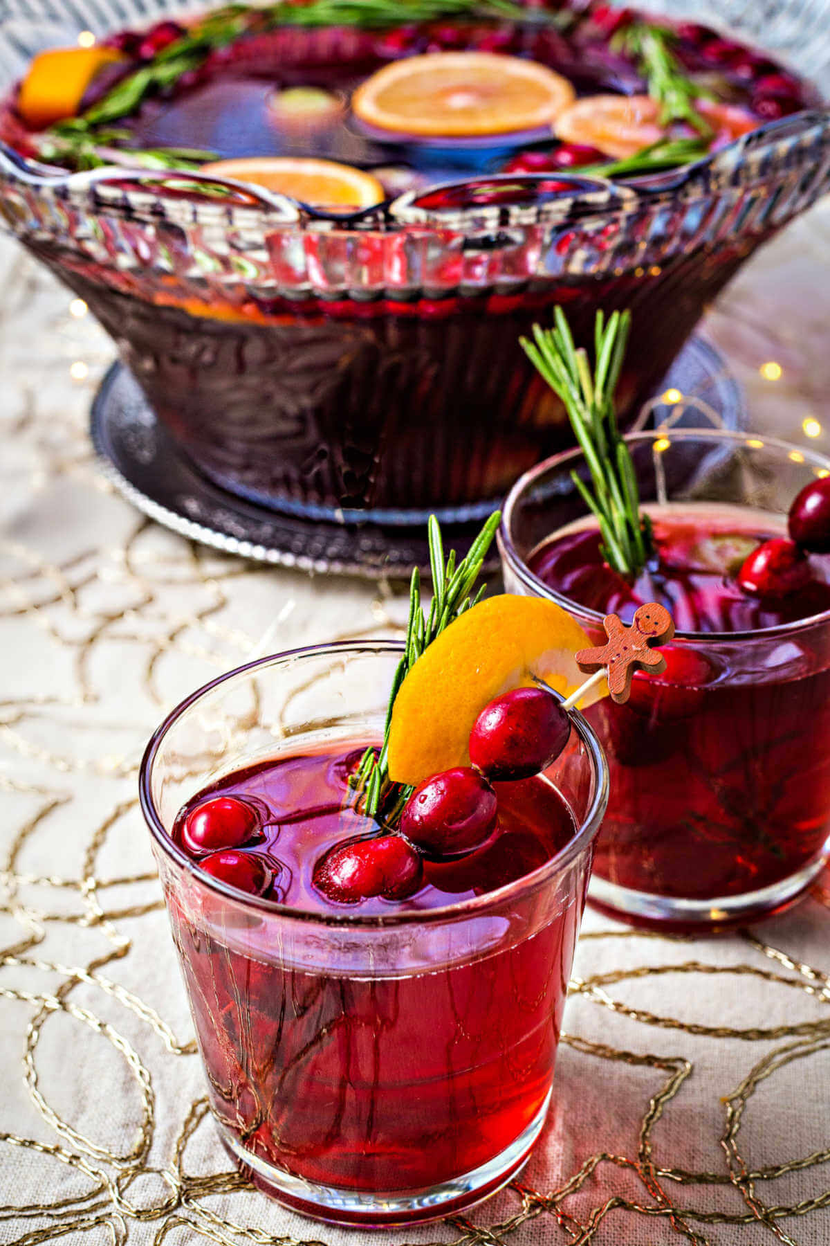 two glasses of cranberry white grape punch on a table with a punch bowl in the background.