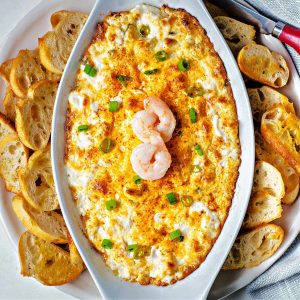 shrimp dip with toasted baguette slices around the plate.