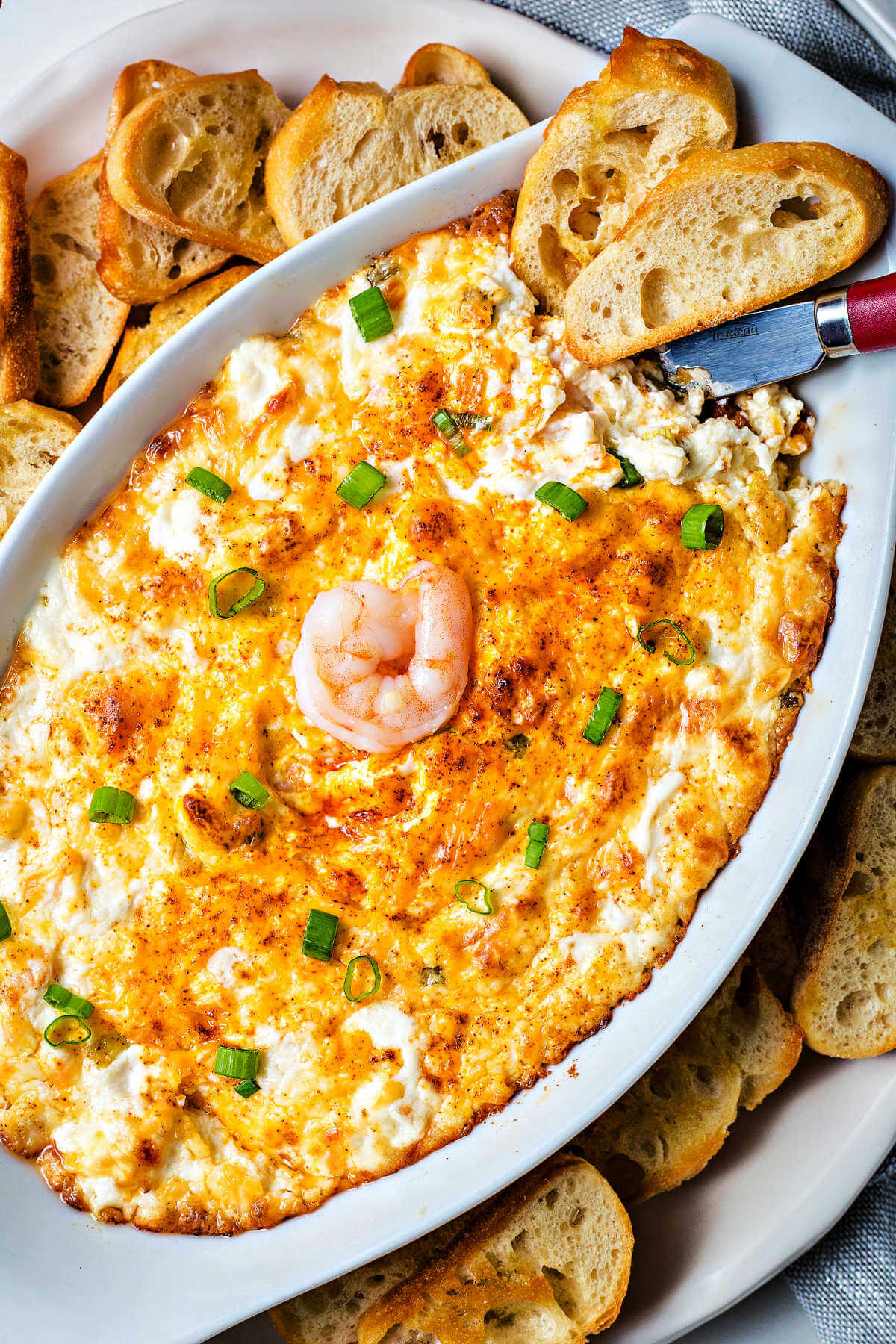 shrimp dip with toasted baguette slices around the plate.